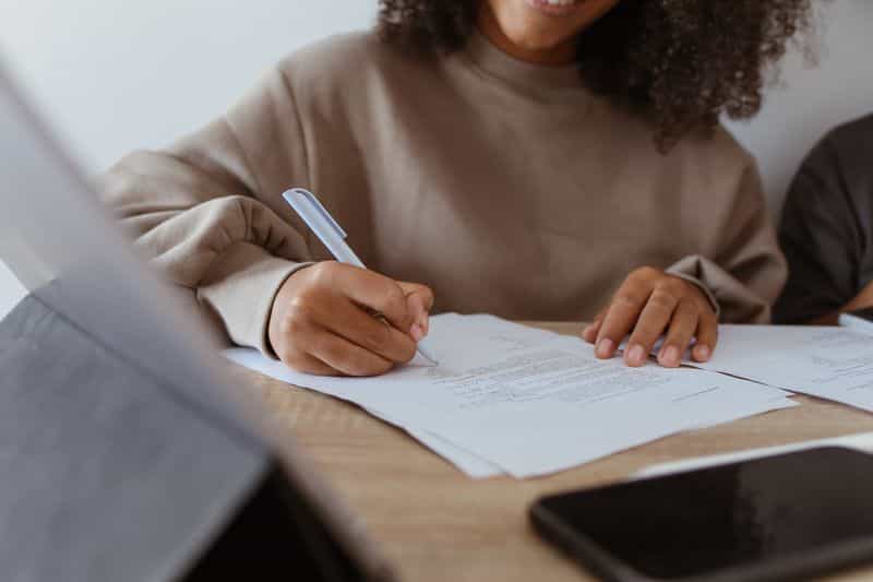 A close-up of a person marking up a printed page with a ballpoint pen at a desk