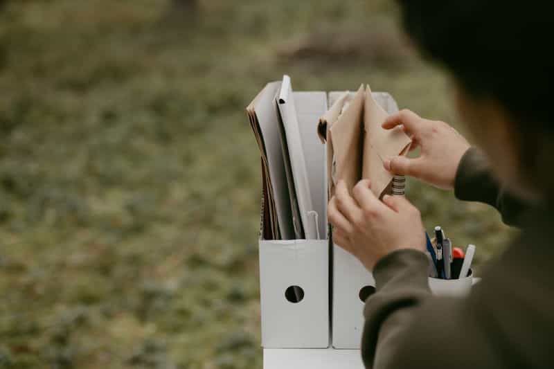 A person selecting one folder from a row of filed documents